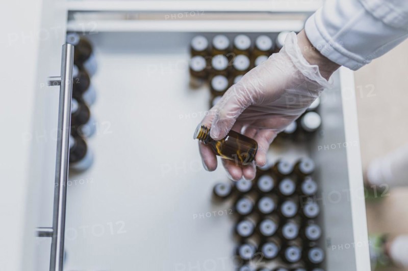 A prescription worker takes a dropper bottle from a drawer