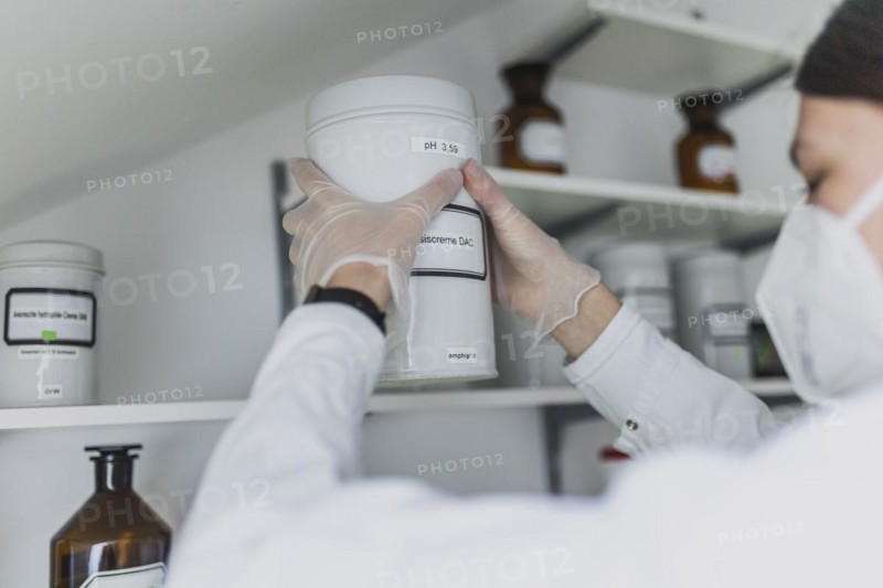 An employee in a pharmacy uses a stand-up container with base cream DAC in the prescription