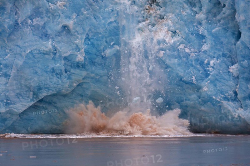 Huge ice chunk breaking from the edge of the Kongsbreen glacier calving into Kongsfjorden