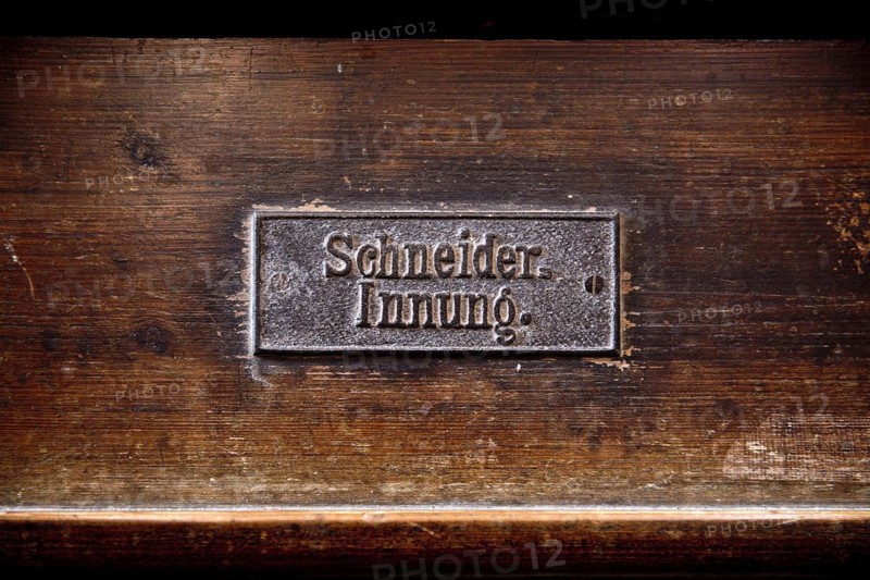 Permanently mounted sign of the tailors' guild on the church pew in the Nikolaikirche