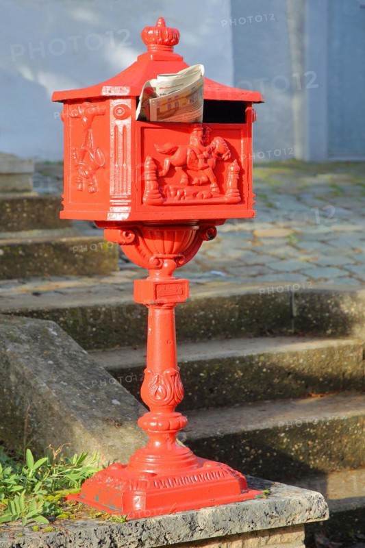Historic red letterbox with newspaper as mail