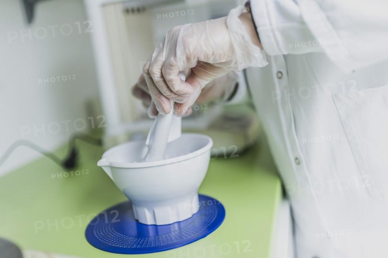 A prescription employee mixes an olive ointment in a fan bowl