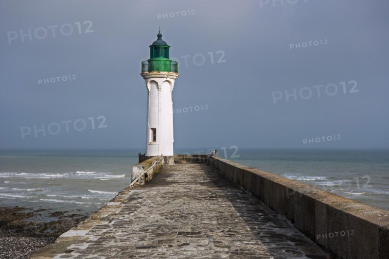 Lighthouse and lonely man looking at sea from pier in the harbour at Saint-Valery-en-Caux