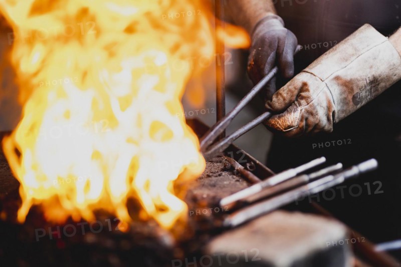 A metalworker works at the forge fire