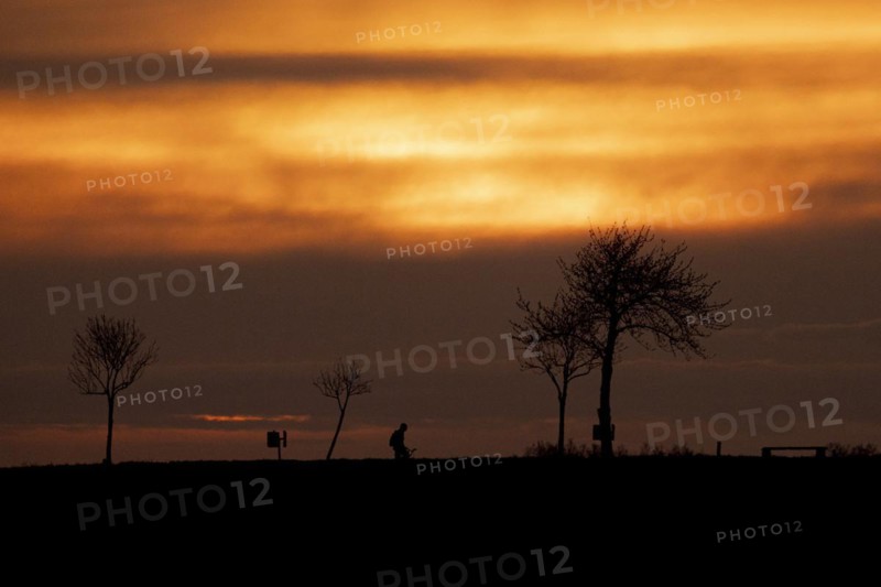 A cyclist silhouetted against the setting sun