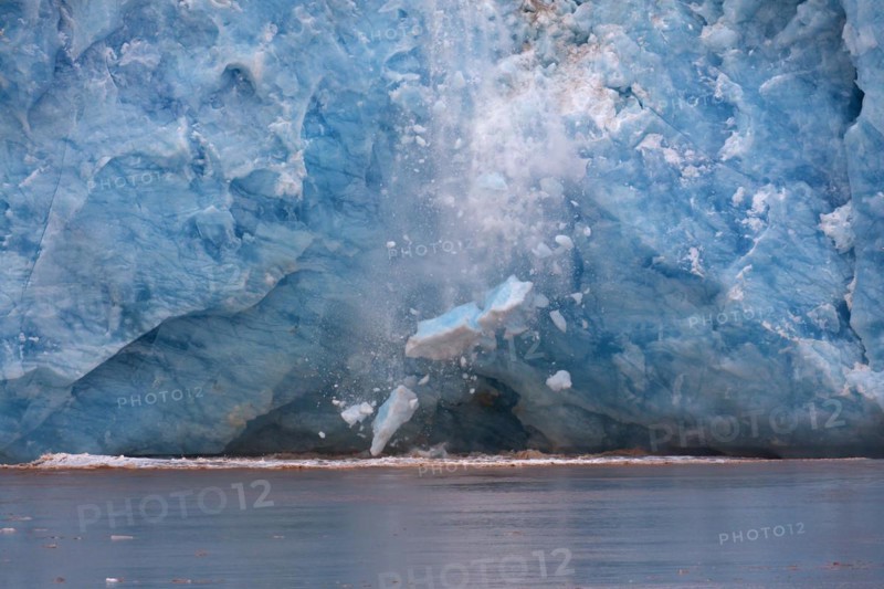 Huge ice chunk breaking from the edge of the Kongsbreen glacier calving into Kongsfjorden