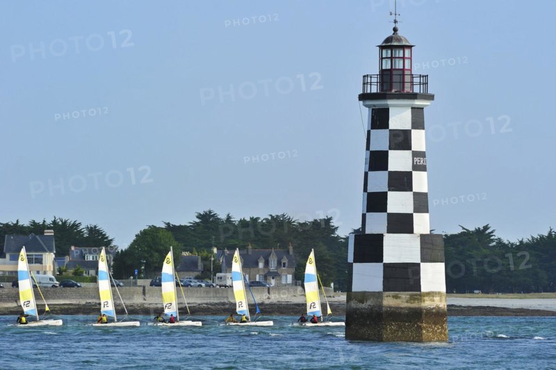 Dinghies from sailing school passing by the lighthouse Perdrix at Loctudy