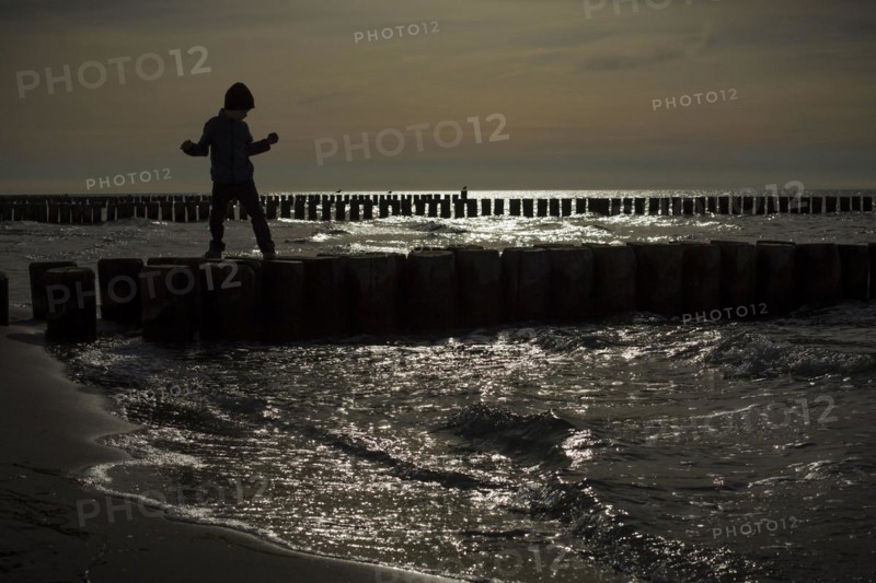 Symbolic photo on the subject of children's fear. A child balances on wooden stilts over the water. Arenshoop