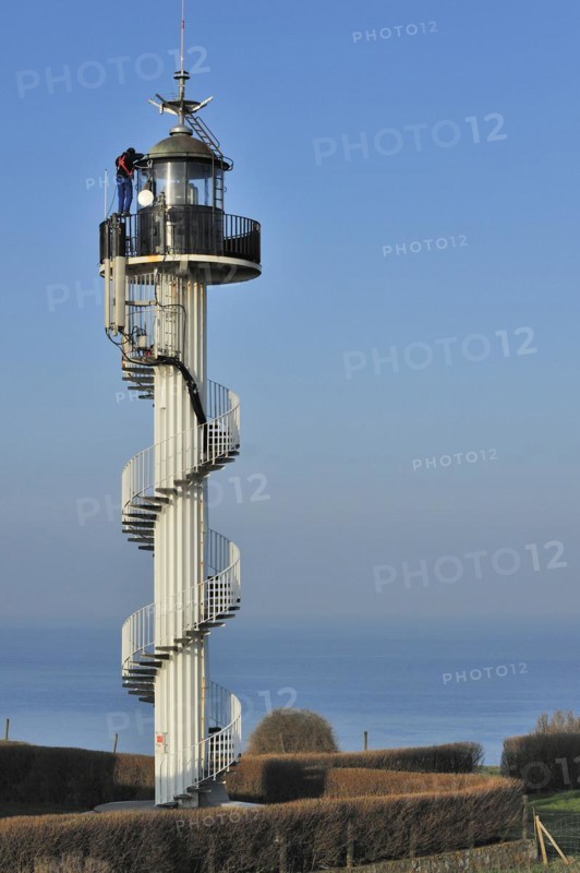Worker wearing safety harness doing maintenance work on the Alprech lighthouse with spiralling exterior staircase near Le Portel