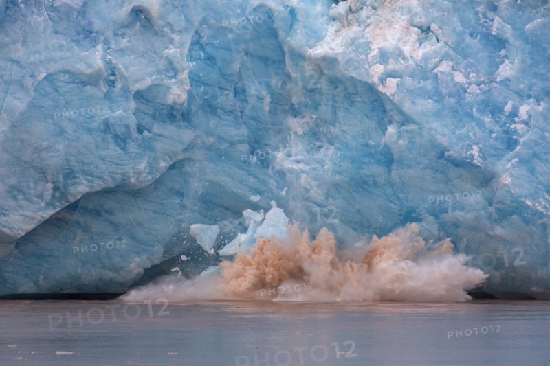 Huge ice chunk breaking from the edge of the Kongsbreen glacier calving into Kongsfjorden