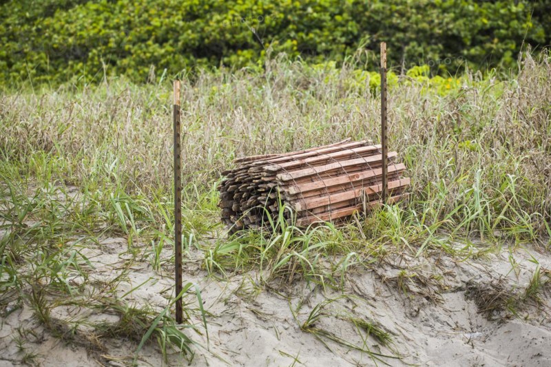 Rolled up fence near fence posts at the beach