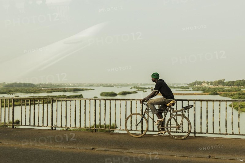 A man drives across a bridge over the Niger River in Bamako