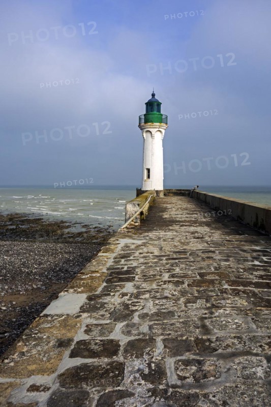 Lighthouse and lonely man looking at sea from pier in the harbour at Saint-Valery-en-Caux