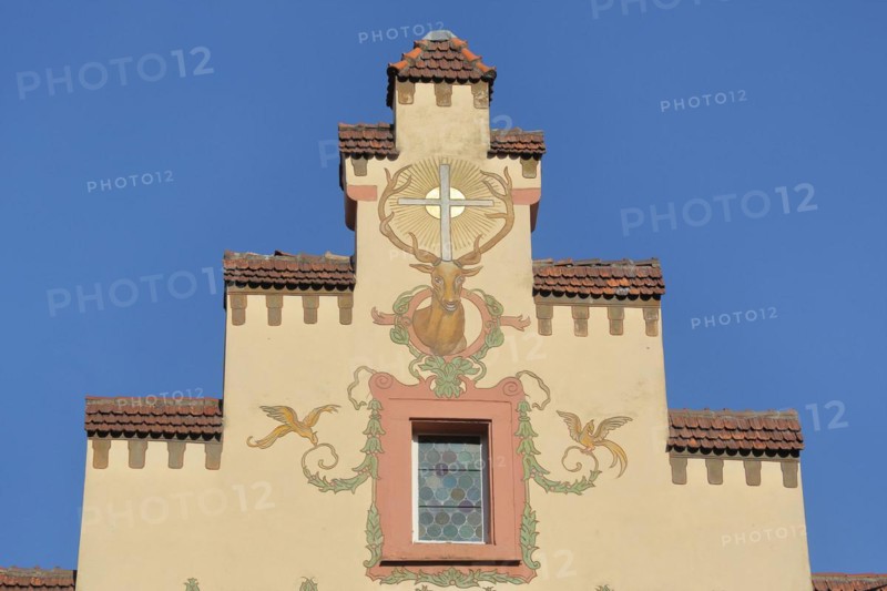 Stepped gable of the historic Deer Pharmacy with mural and stag figure with cross and sun