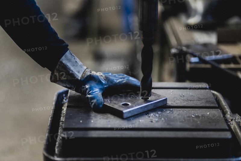 A hole is drilled into a metal plate with a drill