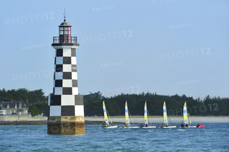 Dinghies from sailing school passing by the lighthouse Perdrix at Loctudy