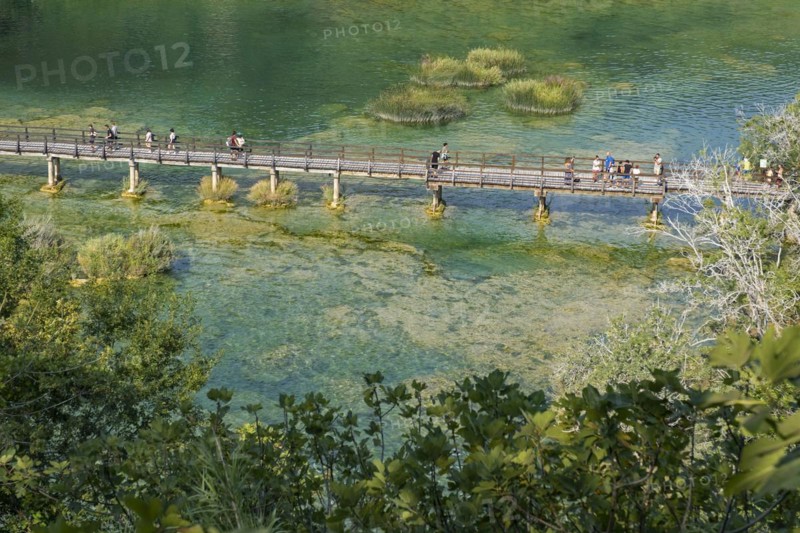 Tourists walking over wooden footbridge over pond in Skradinski buk at the Krka National Park near