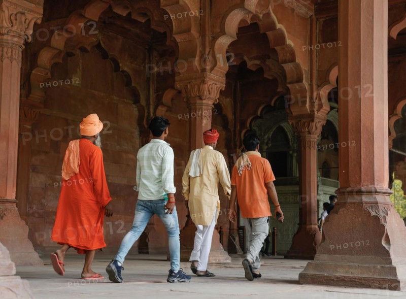 Indian tourists walk through the red sandstone colonnades of the Diwan i Amm in the Red Fort
