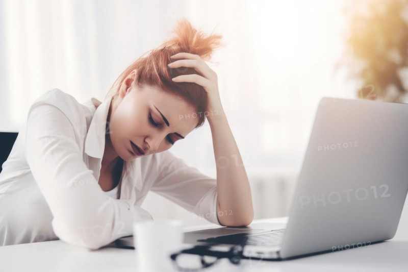 Young woman sitting exhausted at a notebook