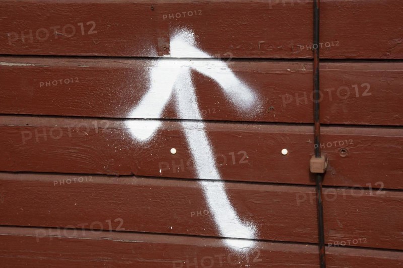A spray-painted white arrow on a board wall points upwards
