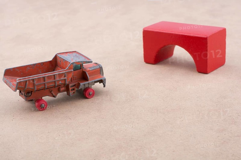 Toy car truck near a brick on a wooden background