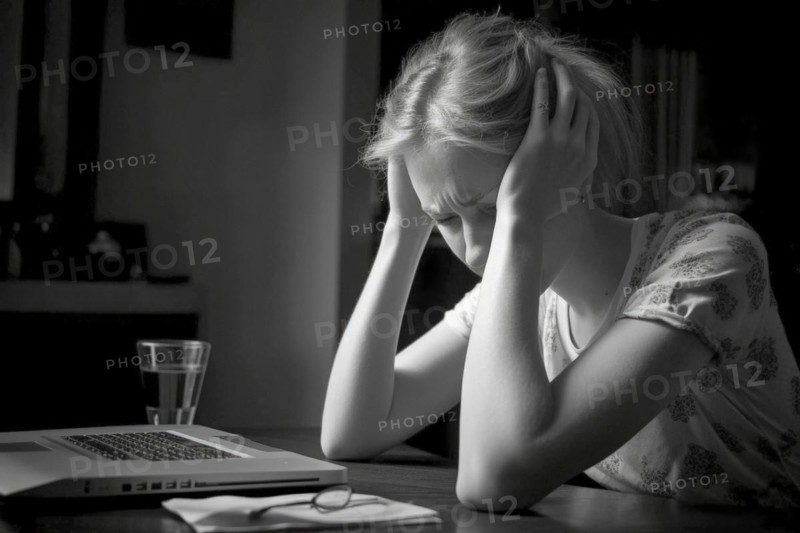 Young woman sitting exhausted at a notebook