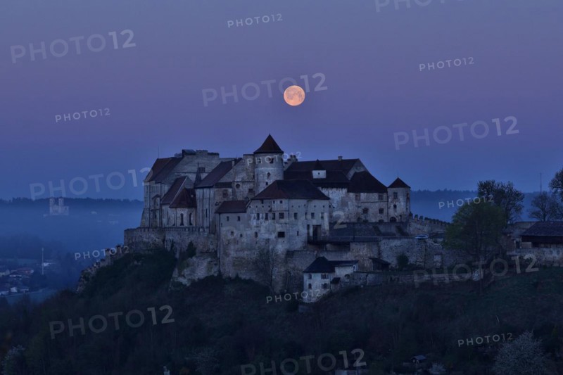 The full moon sets behind the castle in Burghausen