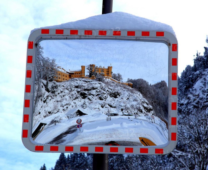 A traffic mirror shows Hohenschwangau Castle in winter