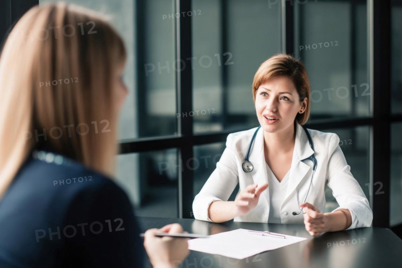 A doctor in a white coat with a stethoscope talking to a patient