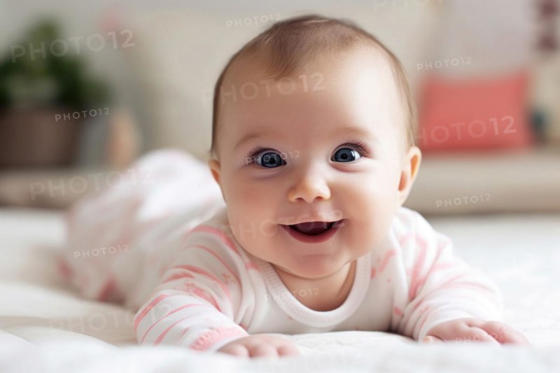 A laughing dark-haired baby in a pink romper suit