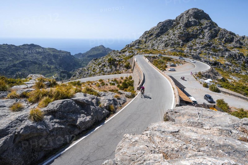 Road cyclists at the mountain pass with serpentines to Sa Colobra