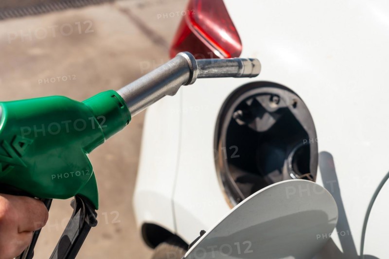 Close-up of a hand with the gun refueling gasoline or diesel fuel in a white car. Concept of transportation