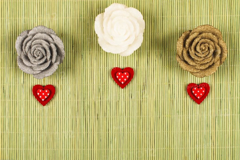 3 decorative roses with 3 small red hearts on a green background