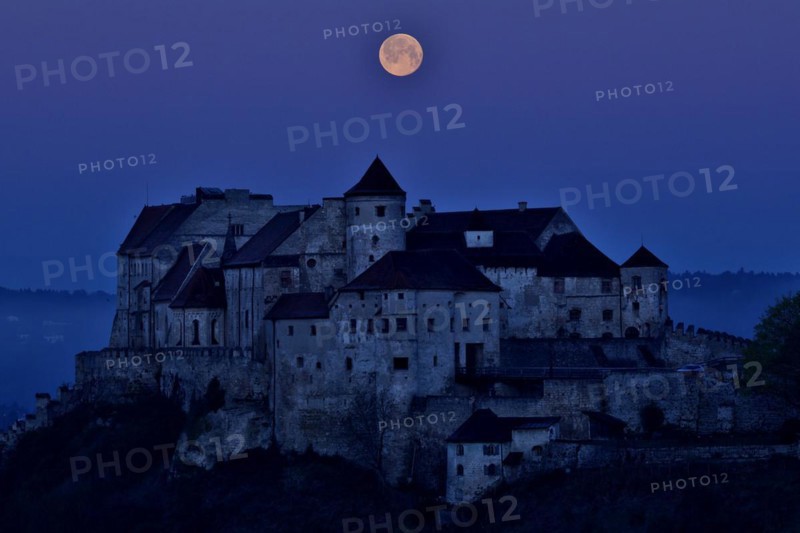 The full moon sets behind the castle in Burghausen