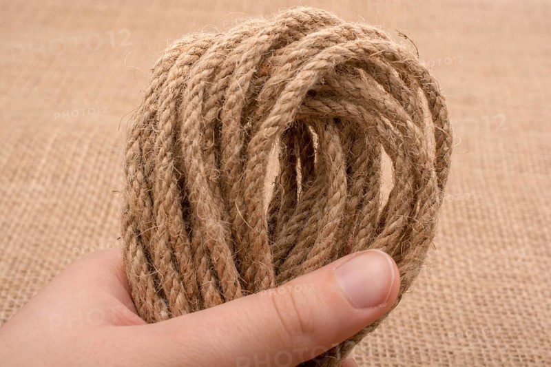 Bundle of linen rope in hand on a brown background