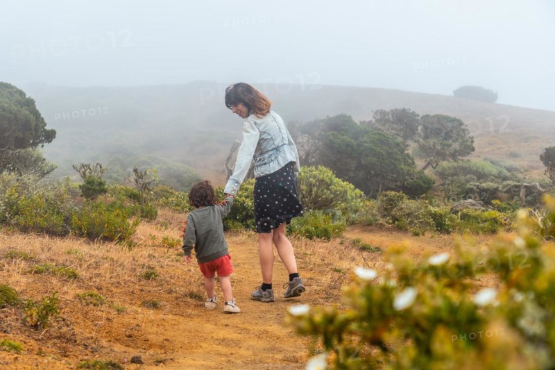 Mother and son walking with flowers to a Sabinar tree twisted by the wind of El Hierro. Canary Islands