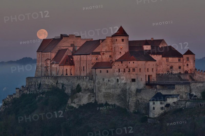The full moon sets behind the castle in Burghausen