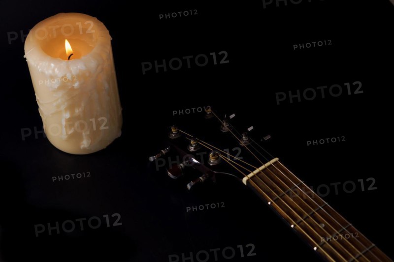 Spanish guitar neck with a candle in the background on a black background