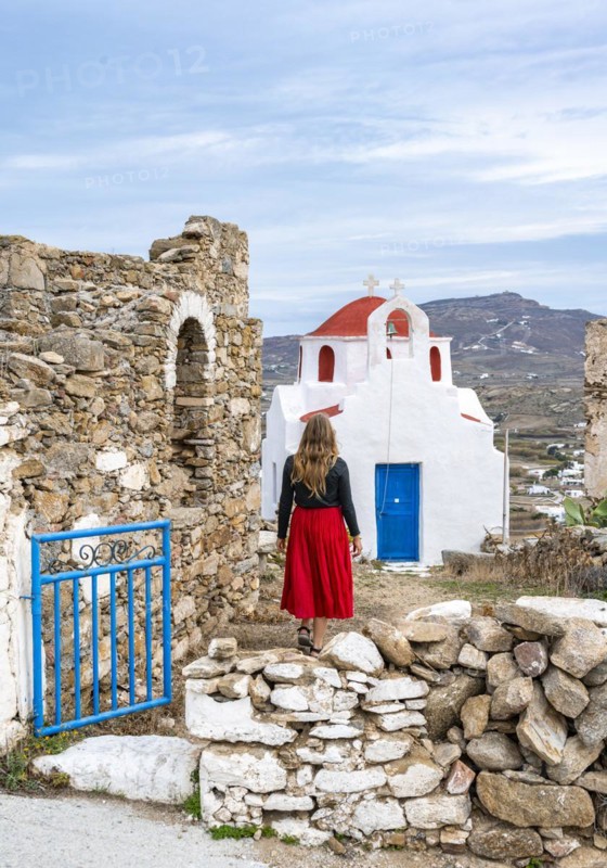 Young woman with red skirt at the entrance gate with ruined wall