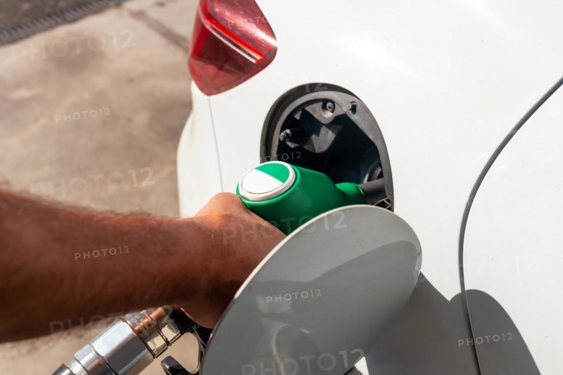 Close-up of a hand with the gun refueling gasoline or diesel fuel in a white car. Concept of transportation