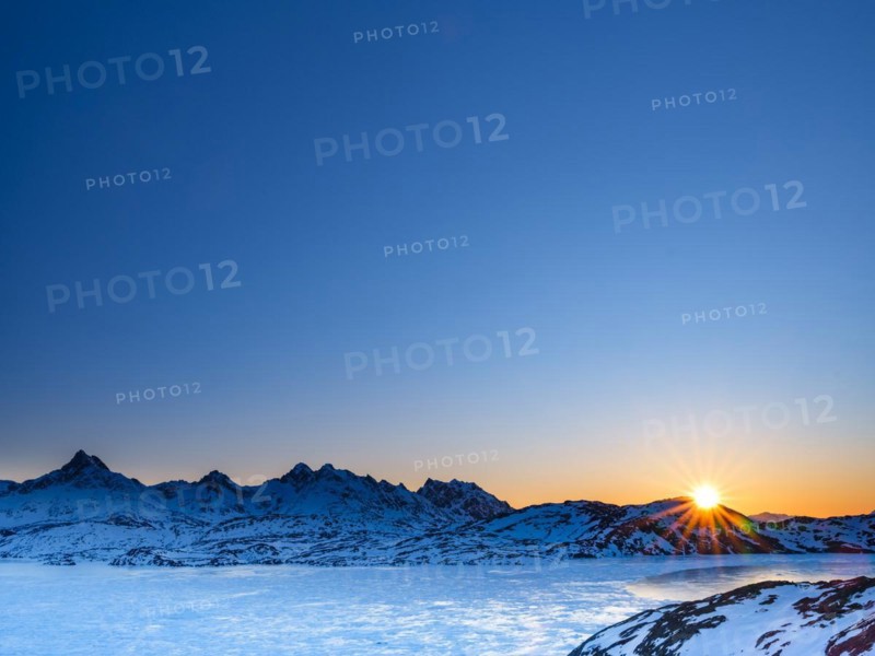 Sunrise over snowy mountains above the frozen Kong Oscar Fjord