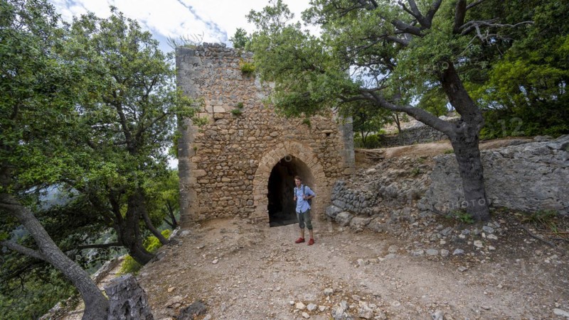 Hikers in front of the tower of the castle ruins Castell Alaro