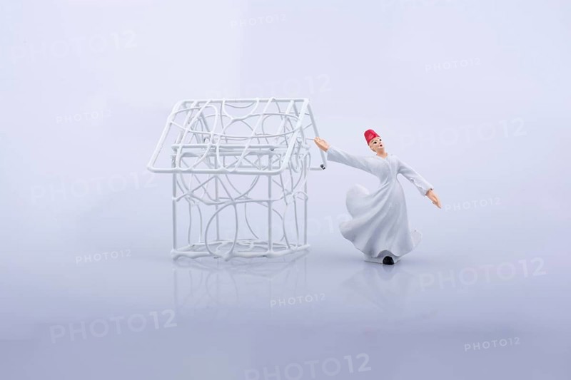 Sufi dervish and a little metal house on a white background