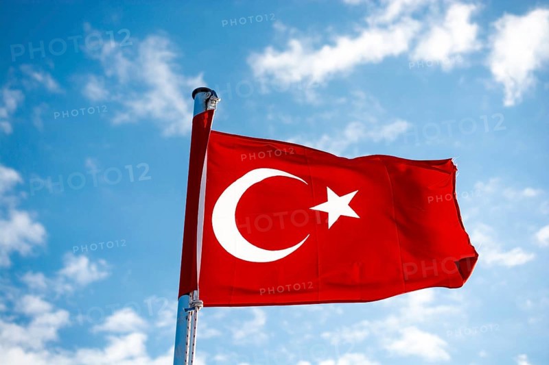 Red Turkish flag on pole on a cloudy sky