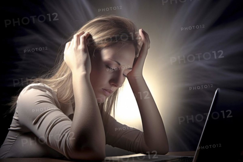 Young woman sitting exhausted at a notebook
