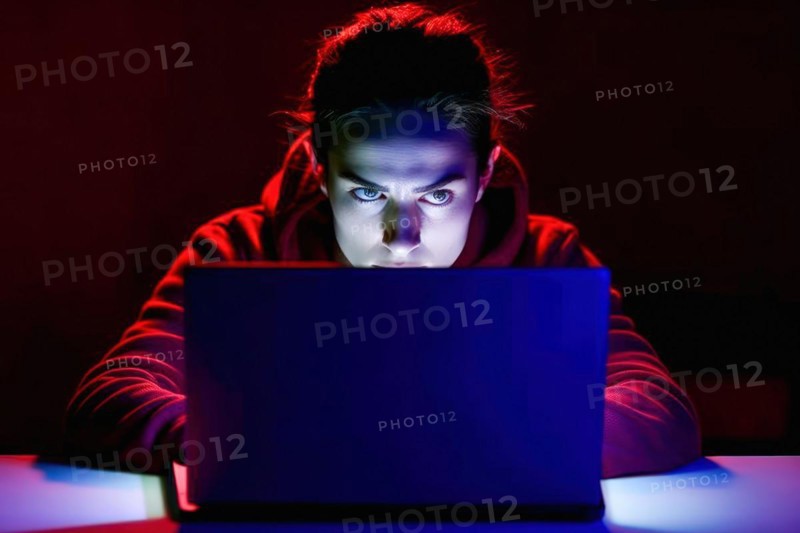 A young woman in her mid-20s works at her laptop at night