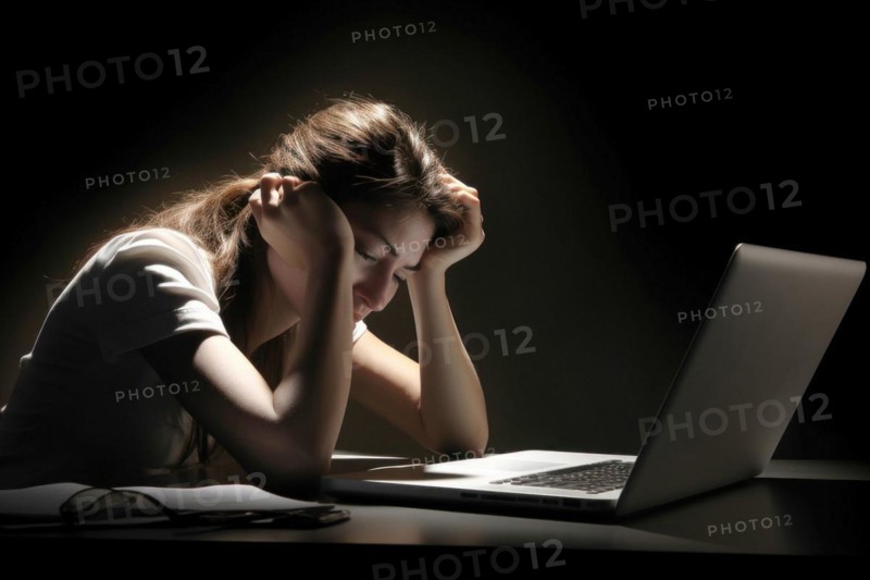 Young woman sitting exhausted at a notebook