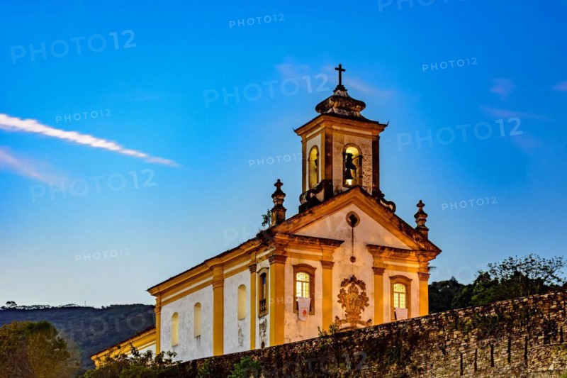Old and historic 18th century church with its facade illuminated at dusk in the city of Ouro Preto