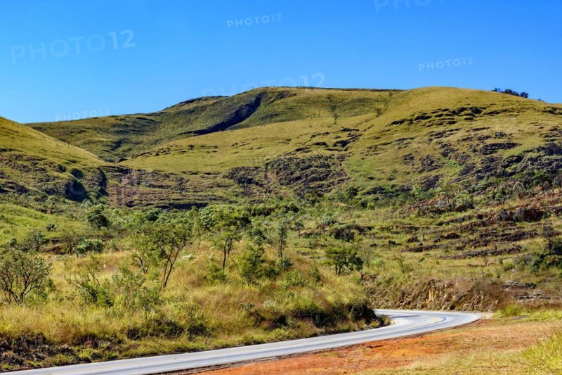 Empty road between the hills with stones and vegetation