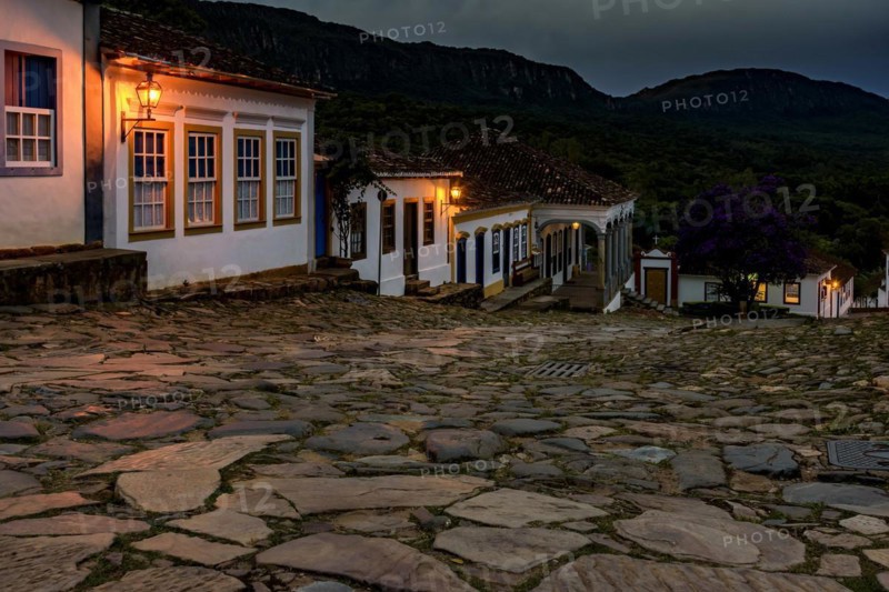 Streets and houses of the historic city of Tiradentes illuminated at dusk with the mountains in the background